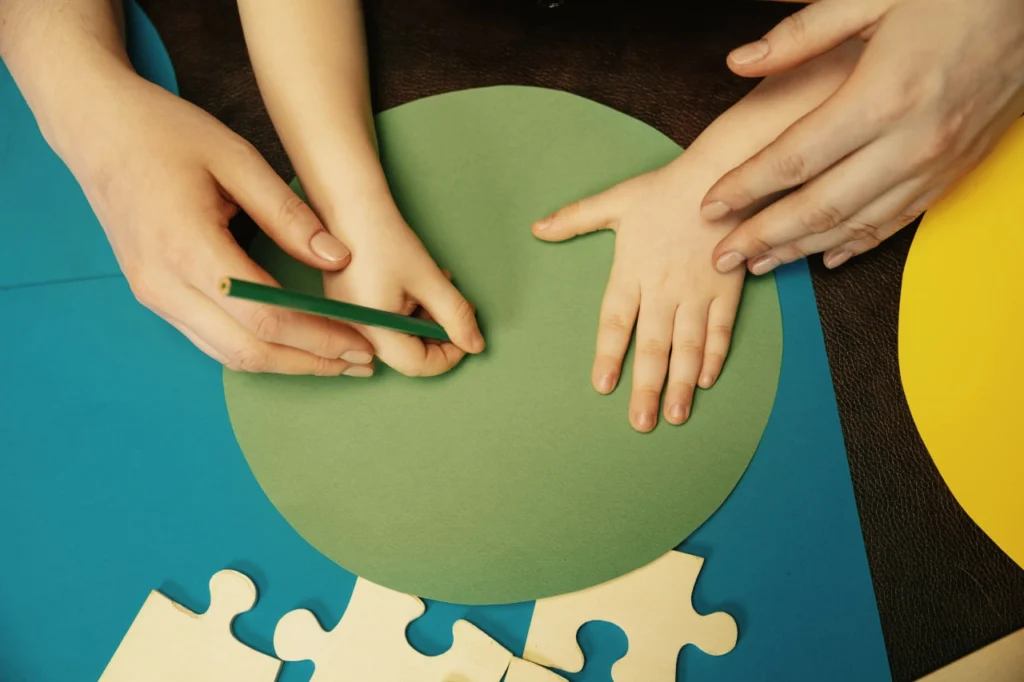 Close-up of parent and child hands creating an art project together at a table