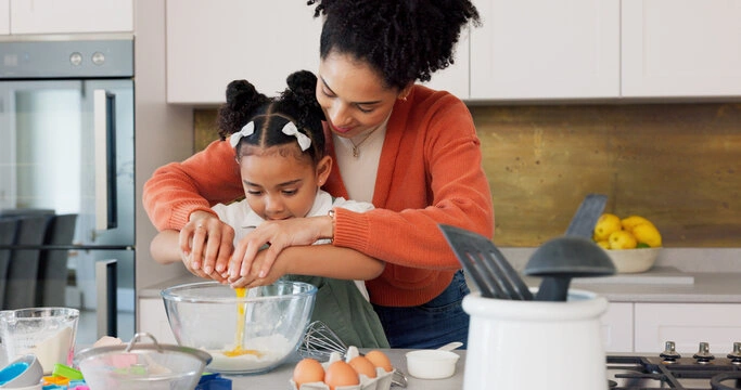 Parent teaching child to cook together in the kitchen, creating connection through everyday activities