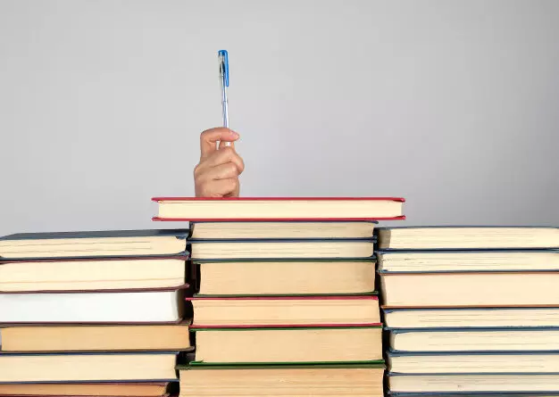 A stack of books and a pen representing the research behind expressive writing.