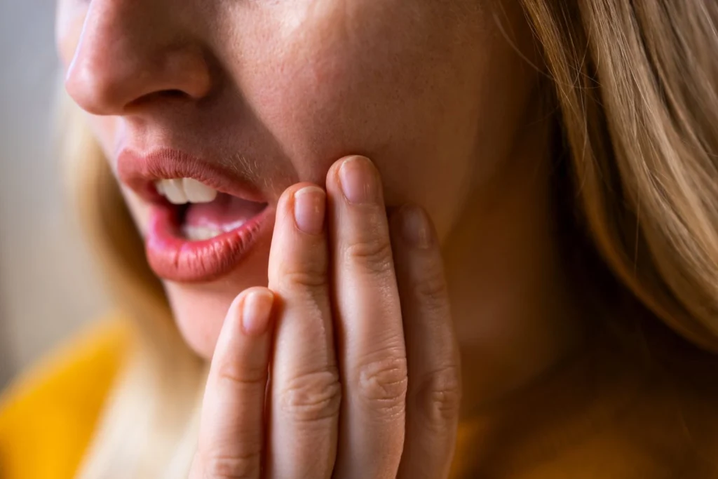 A woman rubbing her jaw to relieve tension caused by stress and teeth grinding.