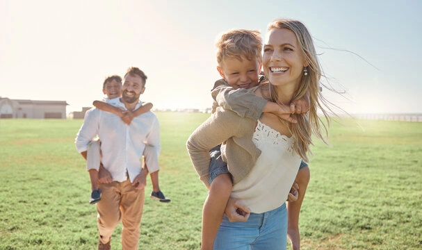 A happy couple in their 40s laughing together outdoors, representing a strong long-term marriage after raising kids.