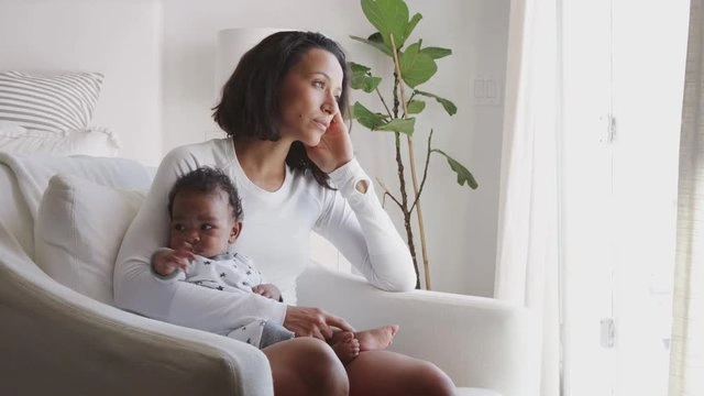 A new mother sitting quietly in thought, reflecting on intrusive thoughts and mental health.