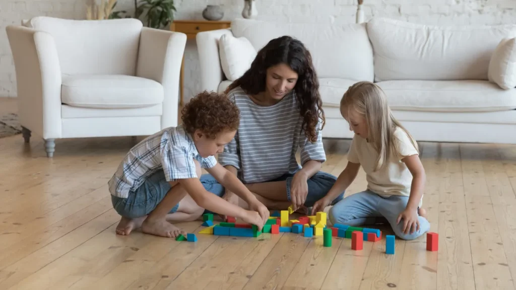 A parent practices a language-building strategy by observing their toddler playing with blocks on the floor.