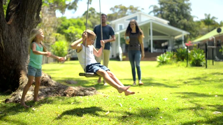 A toddler playing at a park looks back and smiles at their parent, using them as a secure base.