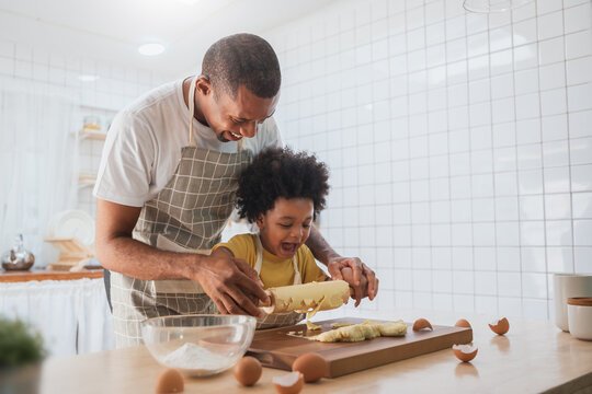 A parent and child smile while cooking together in the kitchen, turning a daily chore into an opportunity for quality time