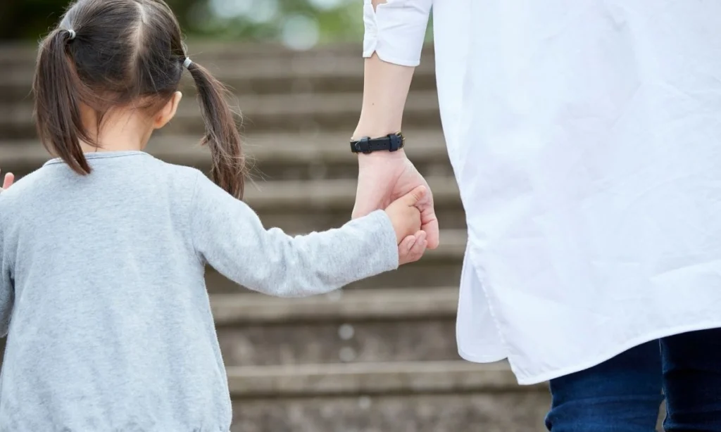 A close-up image of a parent's hand holding a child's hand, symbolizing the security of the parent-child bond.