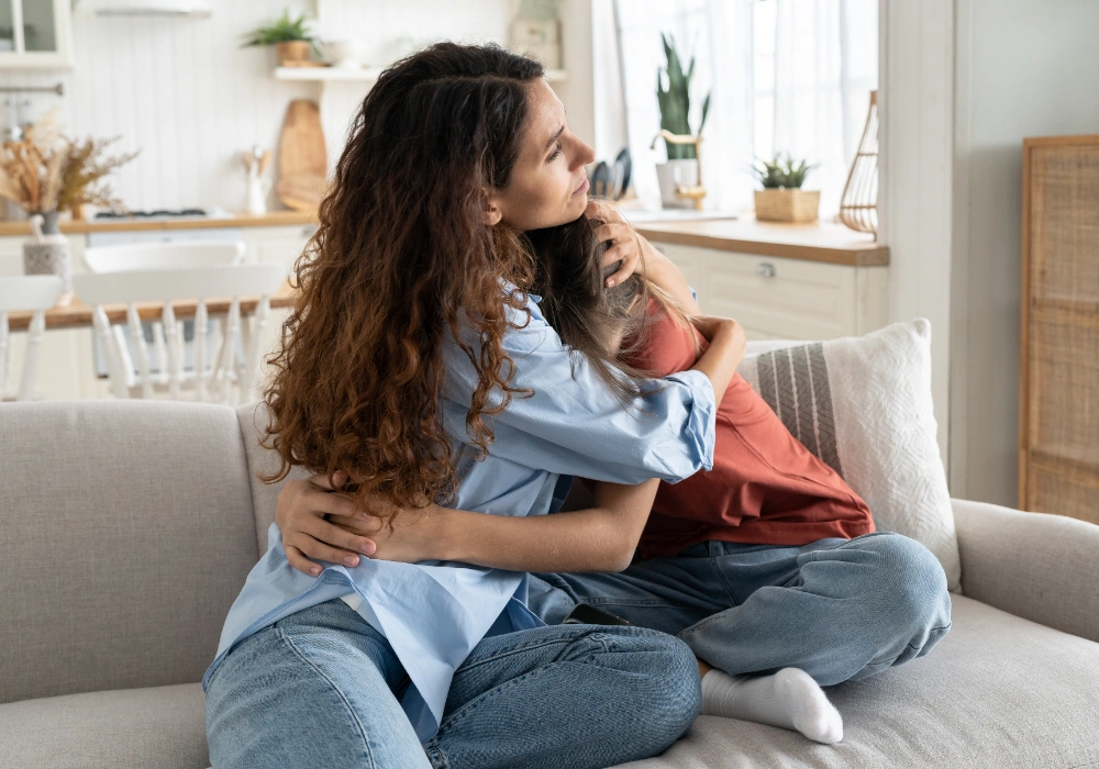 A mother kneeling down to comfort a frustrated toddler to help them regulate their emotions.