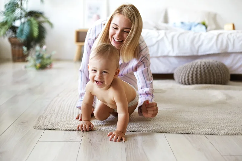 A parent and their toddler laughing together on the living room floor, showing the joyful connection that comes from play.