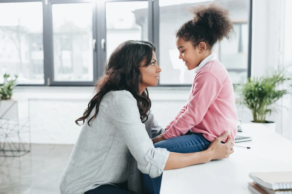 A parent kneels down to comfort and support their child, showing how to handle concerns about social development.