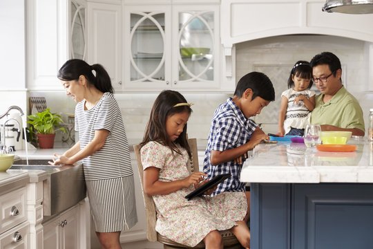 A parent multitasks in the kitchen, representing the everyday stress and mental load of parenting.