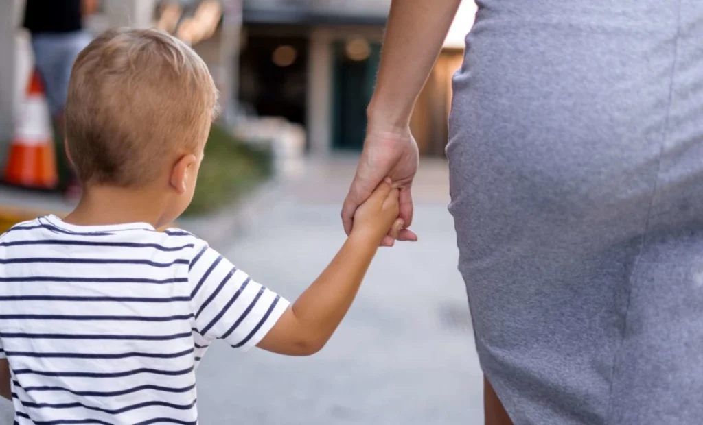 a kid and a mother holding hands and walking