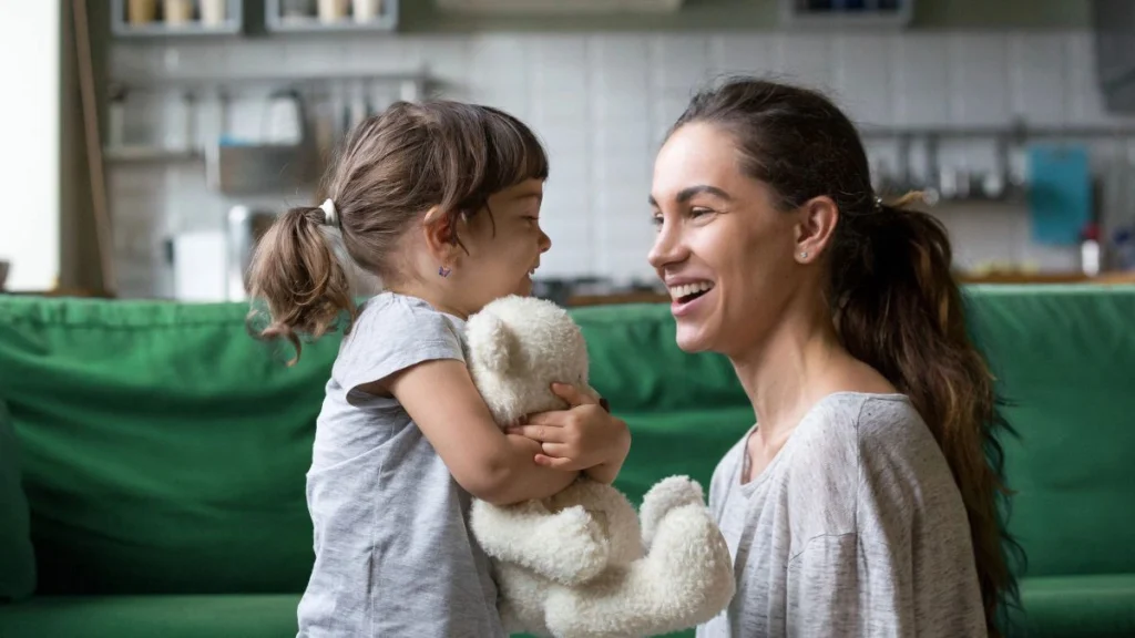 A parent and baby making eye contact and smiling, demonstrating a secure social and emotional connection.
