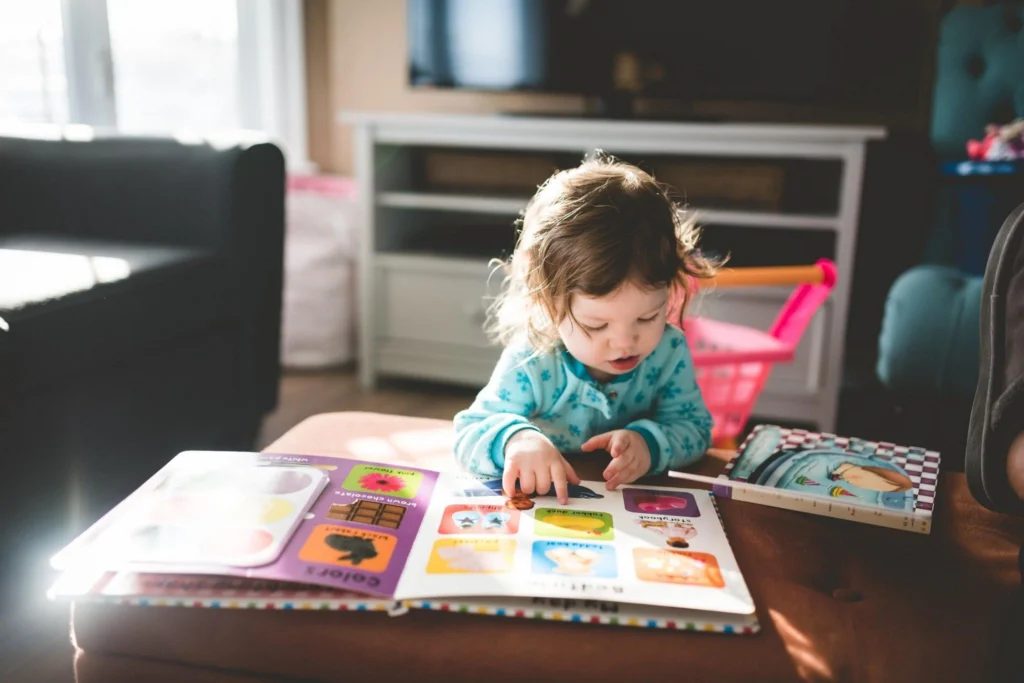 A toddler points at a picture in a board book, a key sign of pre-verbal communication.