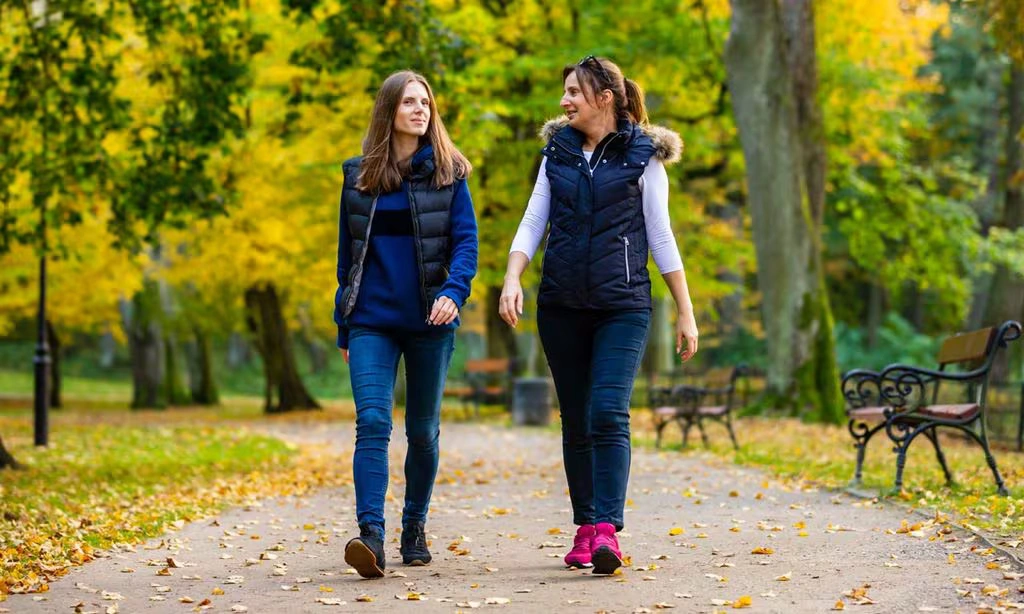 Two friends walking together in a park engaging in deep conversation.