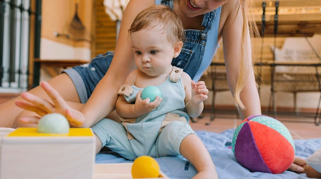 A baby and parent playing with a sensory toy to help encourage the pincer grasp milestone.
