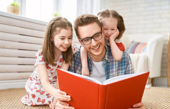 A parent pointing at images in a board book while reading to a toddler to boost vocabulary skills.