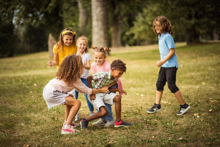 Two young children talking and playing together outdoors, developing social language skills.