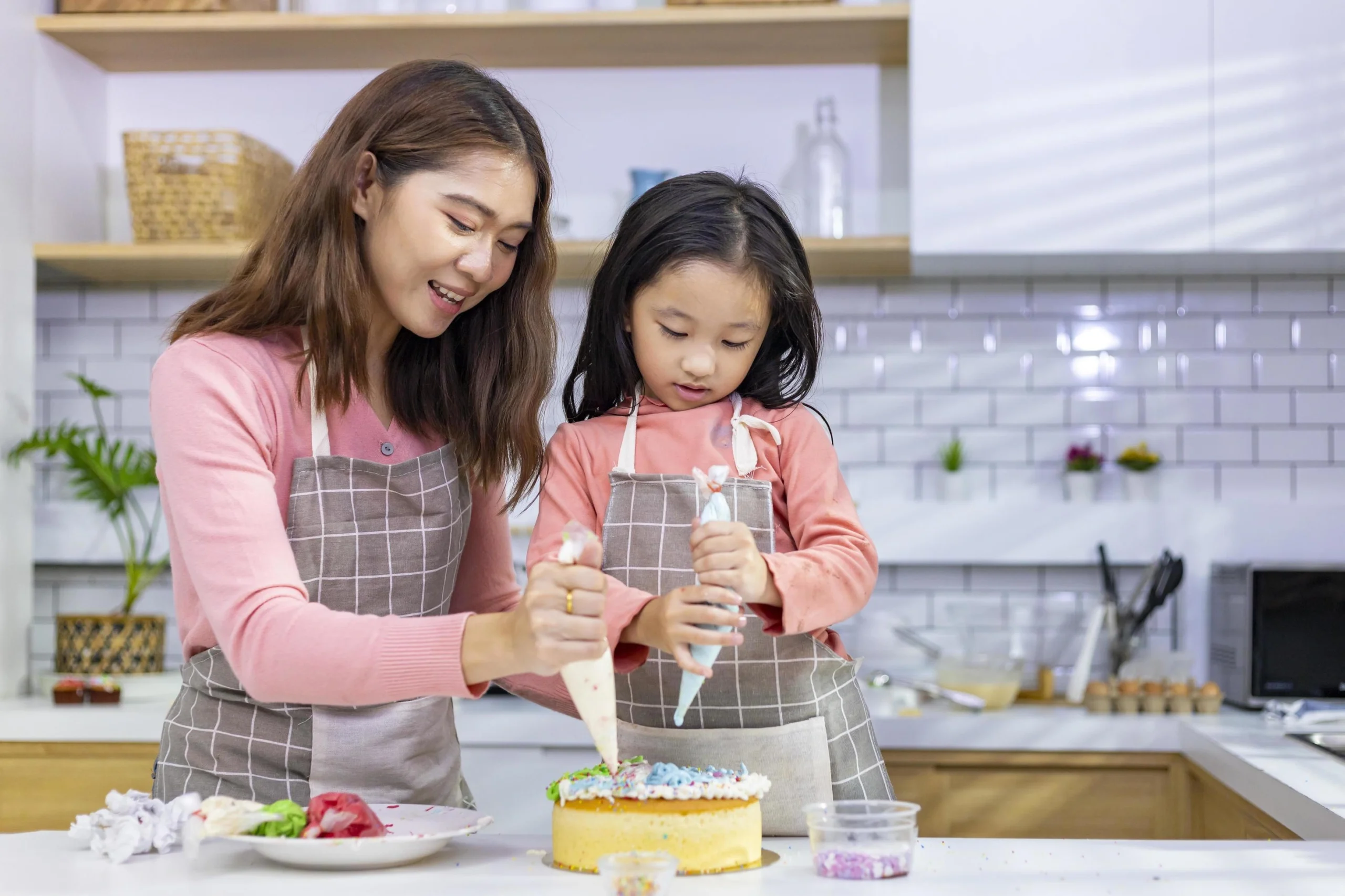 A mother teaching her young daughter how to prepare a traditional family recipe, illustrating the social scaffold of learning.