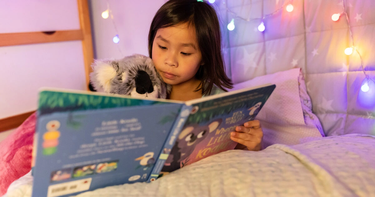 child reading a book at bedtime without screens to support healthy sleep