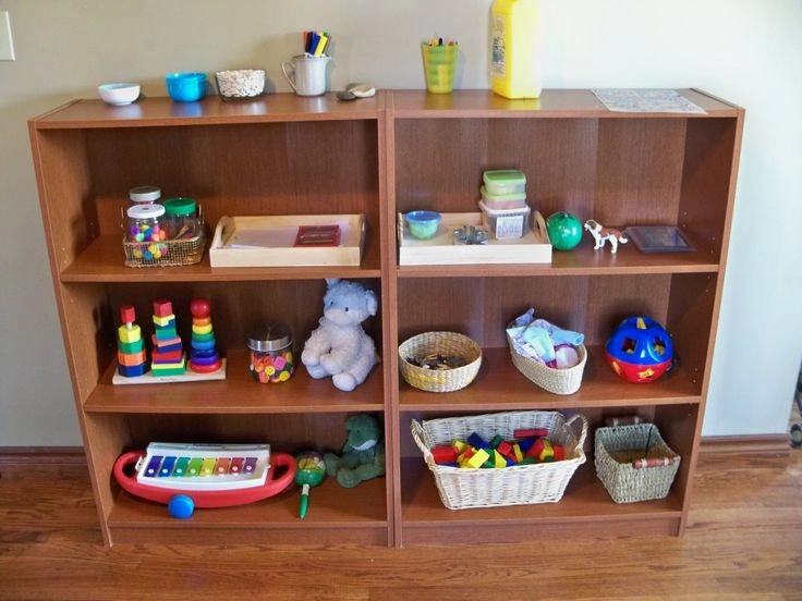 A low, organized wooden shelf with a few toys, creating a calm play environment for a child.