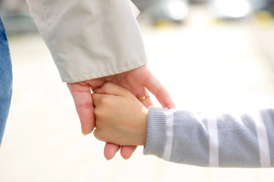 A parent gently holding a child's hand, representing hope and connection that comes from addressing parental anxiety through therapy.