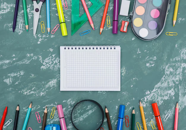 A flat lay of screen-free childhood items including books, crayons, and a magnifying glass representing offline learning activities